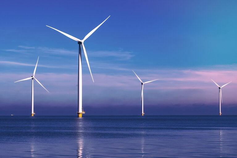 Offshore wind turbines with Ultra High Performance Concrete (UHPC) foundations from Y-MatTec in the sunset at Courseulles-sur-Mer France with blue and violet sky