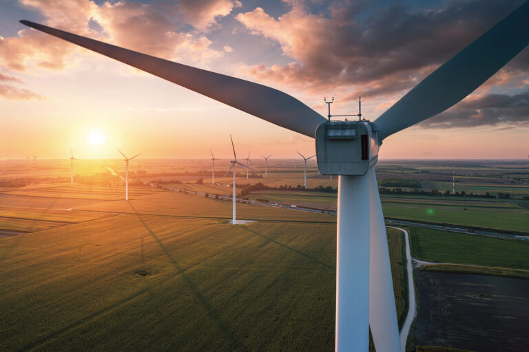 Close up of onshore wind turbine and other wind turbines with Ultra High Performance Concrete (UHPC) foundations from Y-MatTec in the background where the sun is setting in Wambo, Australia